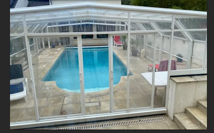 Abri de piscine après nettoyage : les vitrages laissent voir le bassin sans voile ni trace
