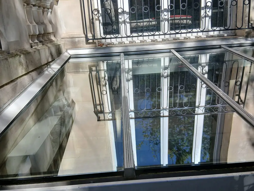 La même verrière après nettoyage : le vitrage reflète nettement les façades et le ciel